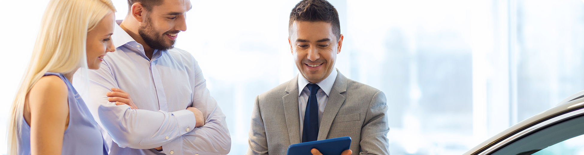 Car dealer working with customers at auto dealership