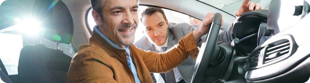 car dealer shows car features to male customer