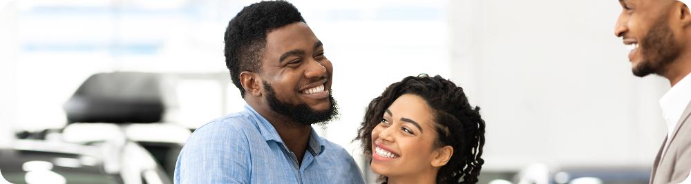 car dealer smiles at happy couple