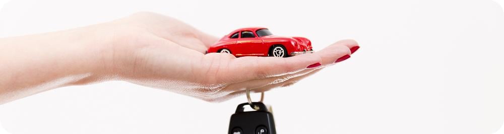 close up hand holding toy car and keys