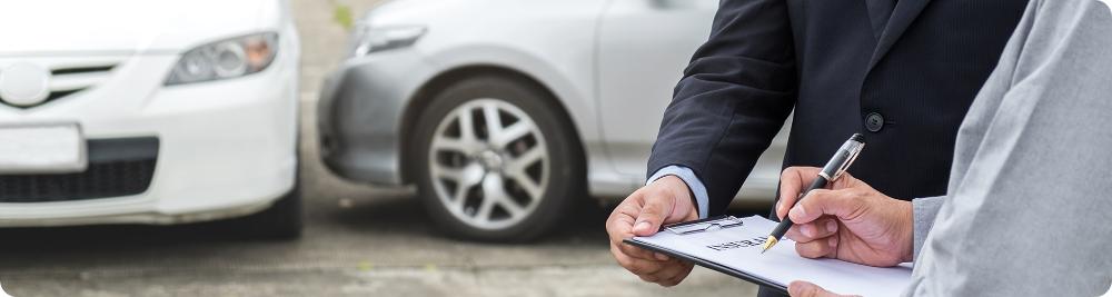 driver signs document next to two cars that have collided