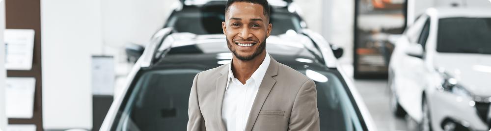 Happy car dealer in front of cars