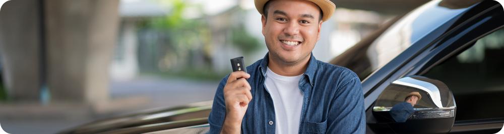 happy man holds key in front of car